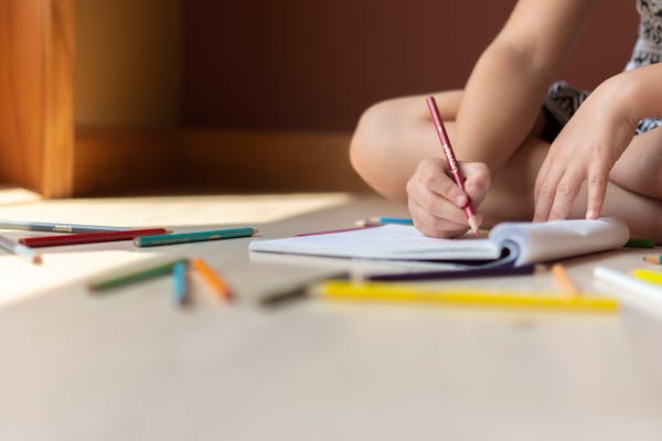 Young child drawing with crayons during fine motor skills therapy